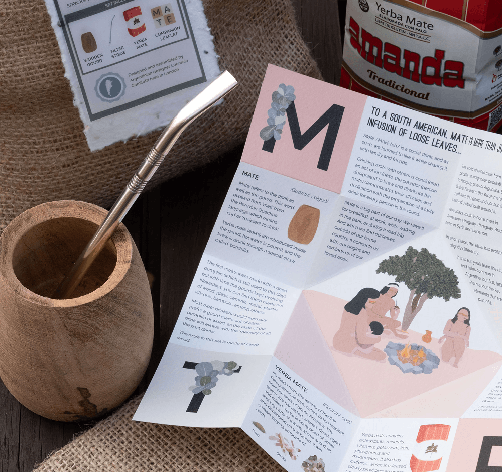 A wooden mate gourd with a metal straw, beside the Yerba Mate Set's companion leaflet and a bag of yerba mate